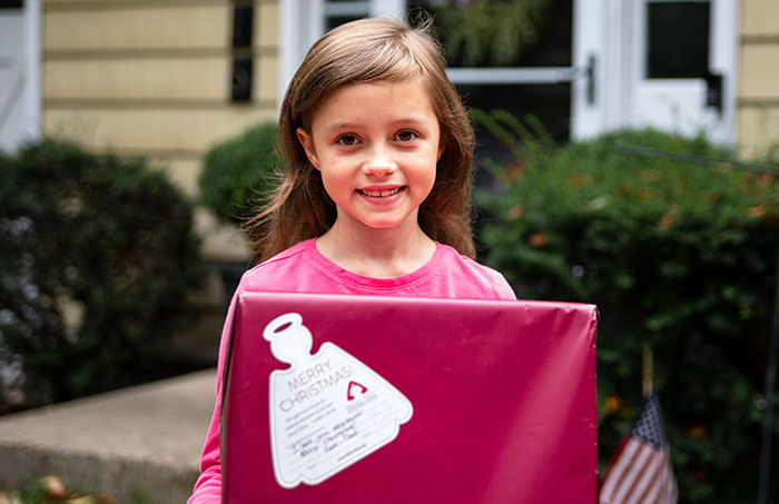 Smiling young girl holding her Angel Tree Christmas gift